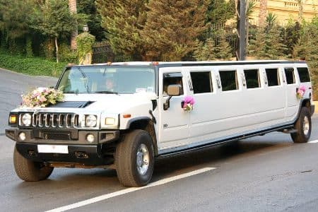 White decorated Hummer Stretch limousine with trees behind