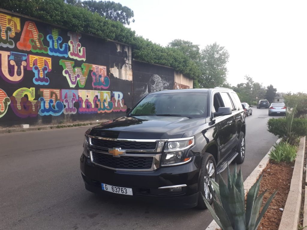 Luxury Tahoe 2020 black parked beside a colorful wall in a luxury area in beirut showing the left side of the car