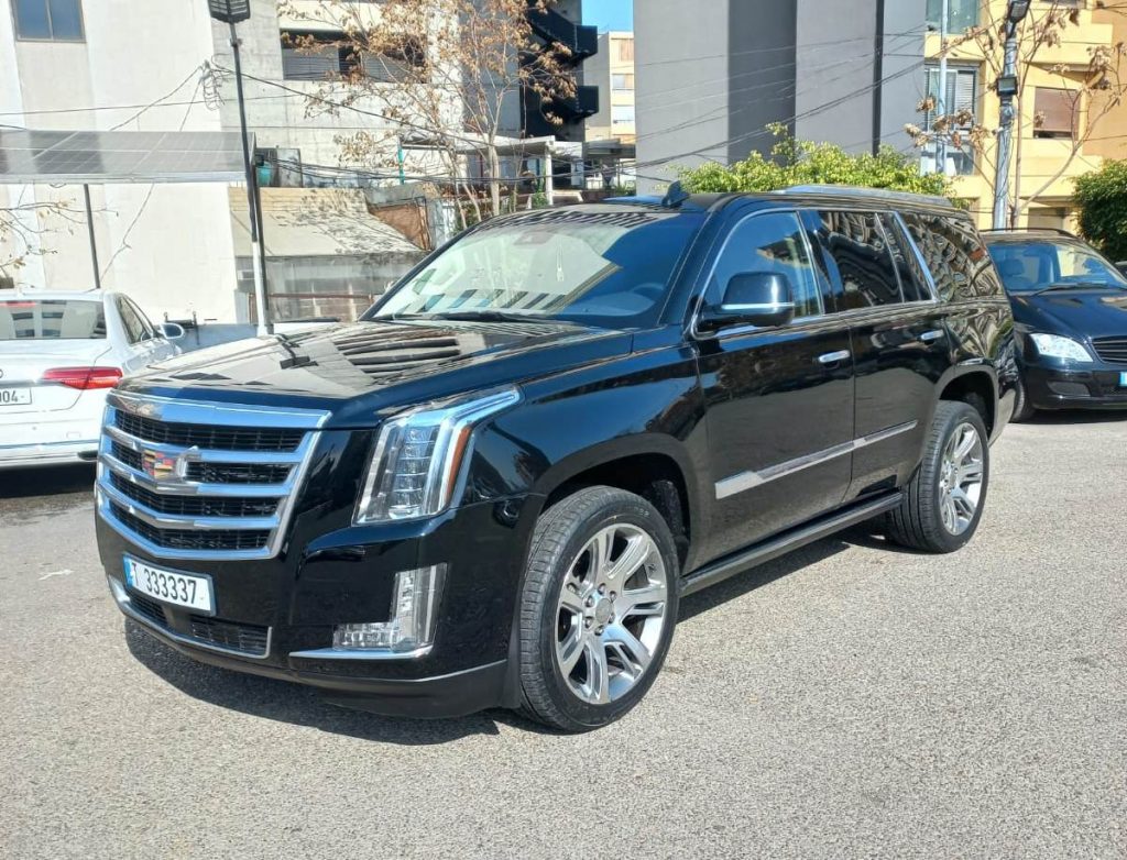 Luxury Cadillac Escalade color black front side parked in a large parking lot
